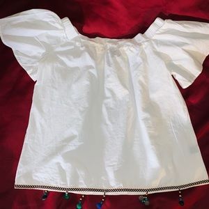 Off-shoulder top with pom poms and chevron edge.